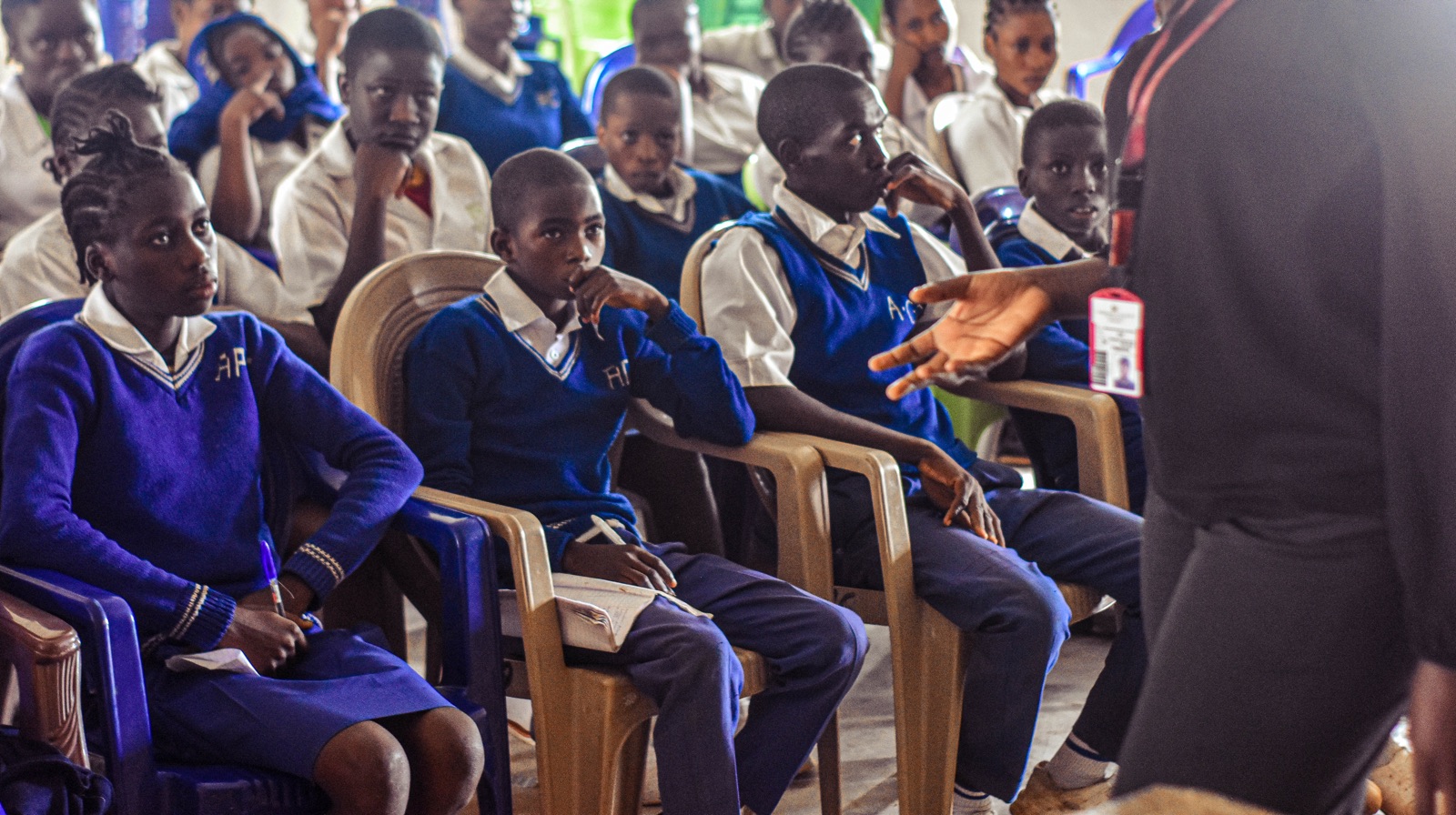 Students in blue uniforms seated in rows during a talk
